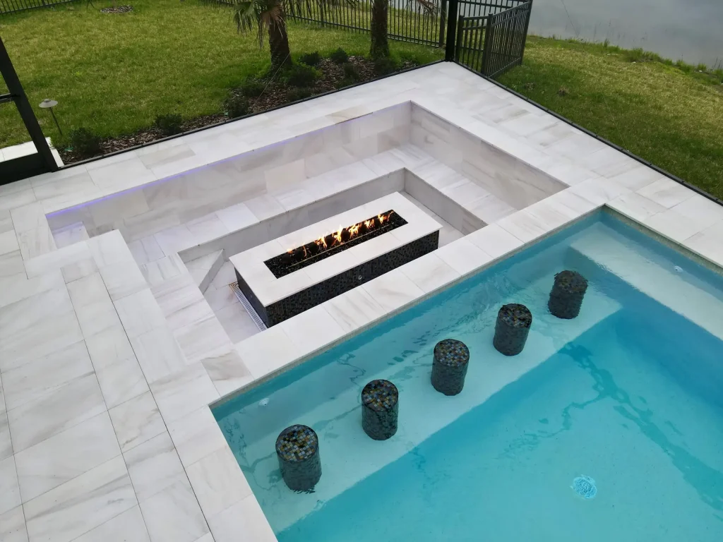 Modern backyard pool with fire feature and decorative stepping stones.