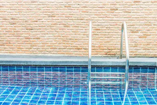 Close-up of a swimming pool with blue tiles and metal ladder.