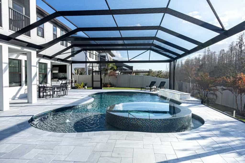Modern backyard pool with hot tub and screened enclosure for outdoor relaxation.